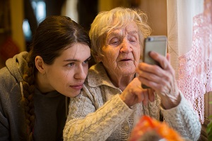 Äldre kvinna med en smart telefon i sällskap med en yngre kvinna