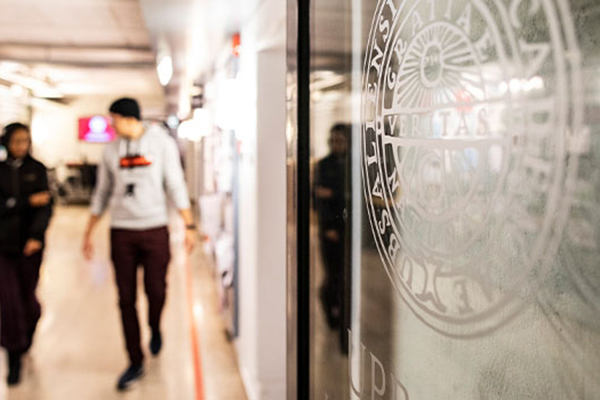 Fotografi på korridor med universitets logotyp inetsad i en glasvägg.