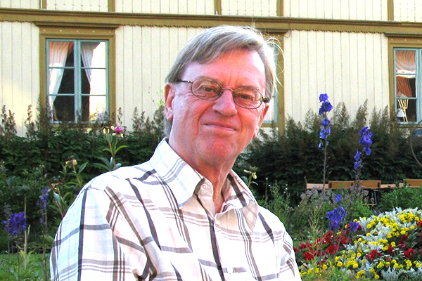 Fotografi på Anders Bäckström sittandes i en trädgård.