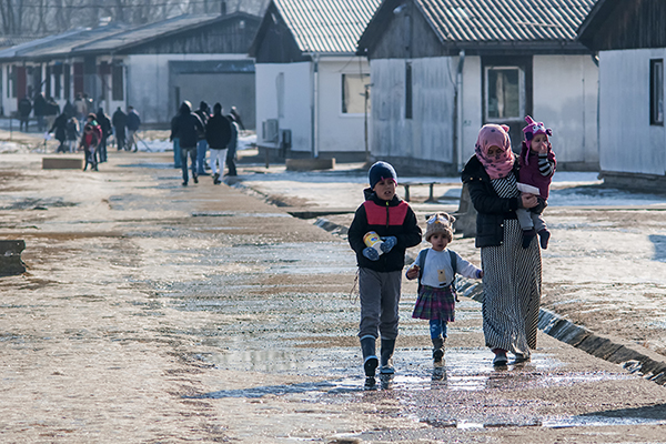 Foto från flyktingläger med barnfamilj som går mot kameran.
