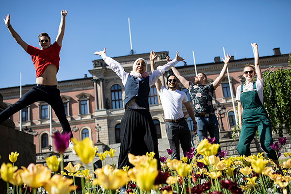 Fem studenter som hoppar framför universitetshuset