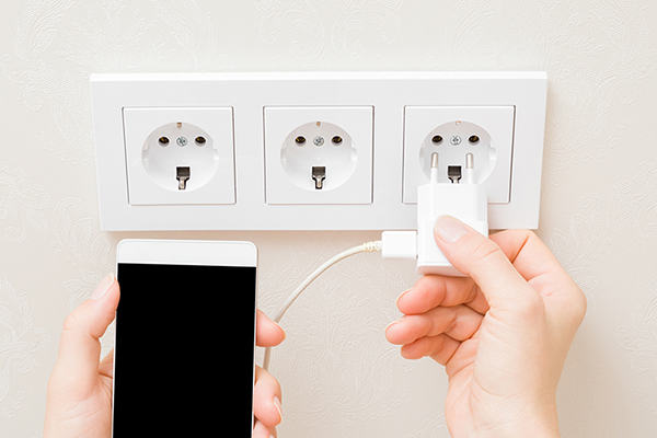 Unplugged mobile phone charger by a wall socket.
